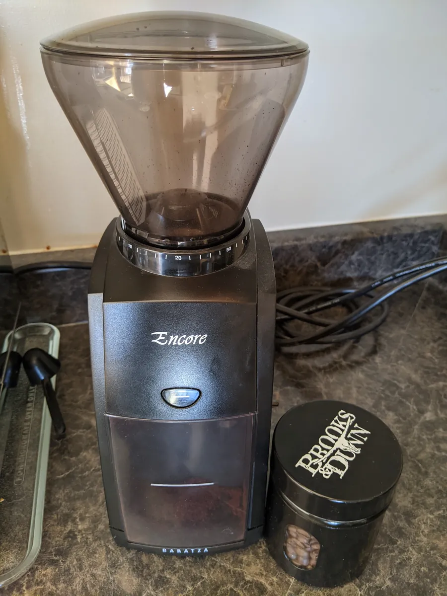 Black Baratza Encore original coffee grinder with its bean hopper, front pulse button and grounds bin.